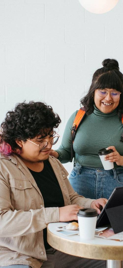 two students working together side by side wuth a laptop